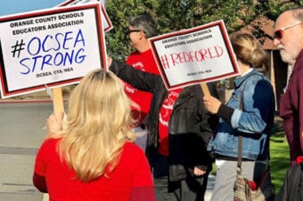 People holding up protest signs outside near a curb facing the street
