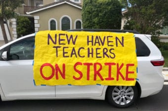 White mini van parked with yellow sign New Haven Teachers on Strike