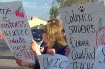 Person holding a protest sign standing looking away