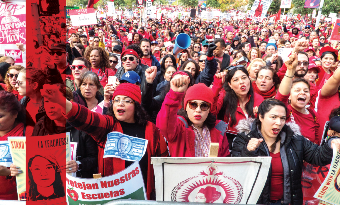 A sea of educators wearing red chants together and hold their firsts in the air, holding signs saying Stand with LA Teachers