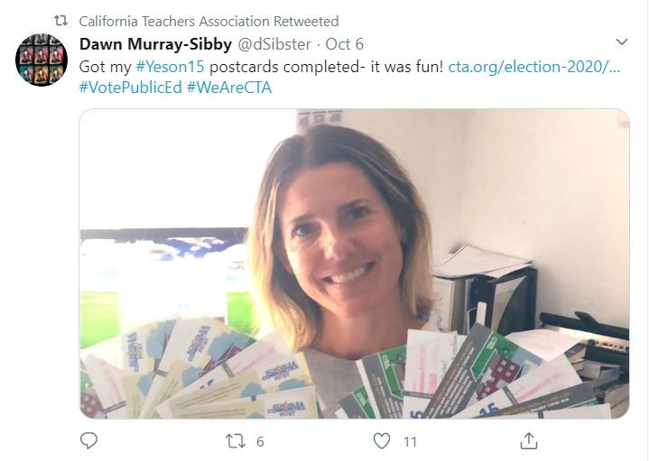 Teacher holding Yes on 15 postcards