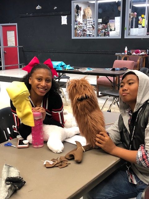 Two girls working on making puppets.