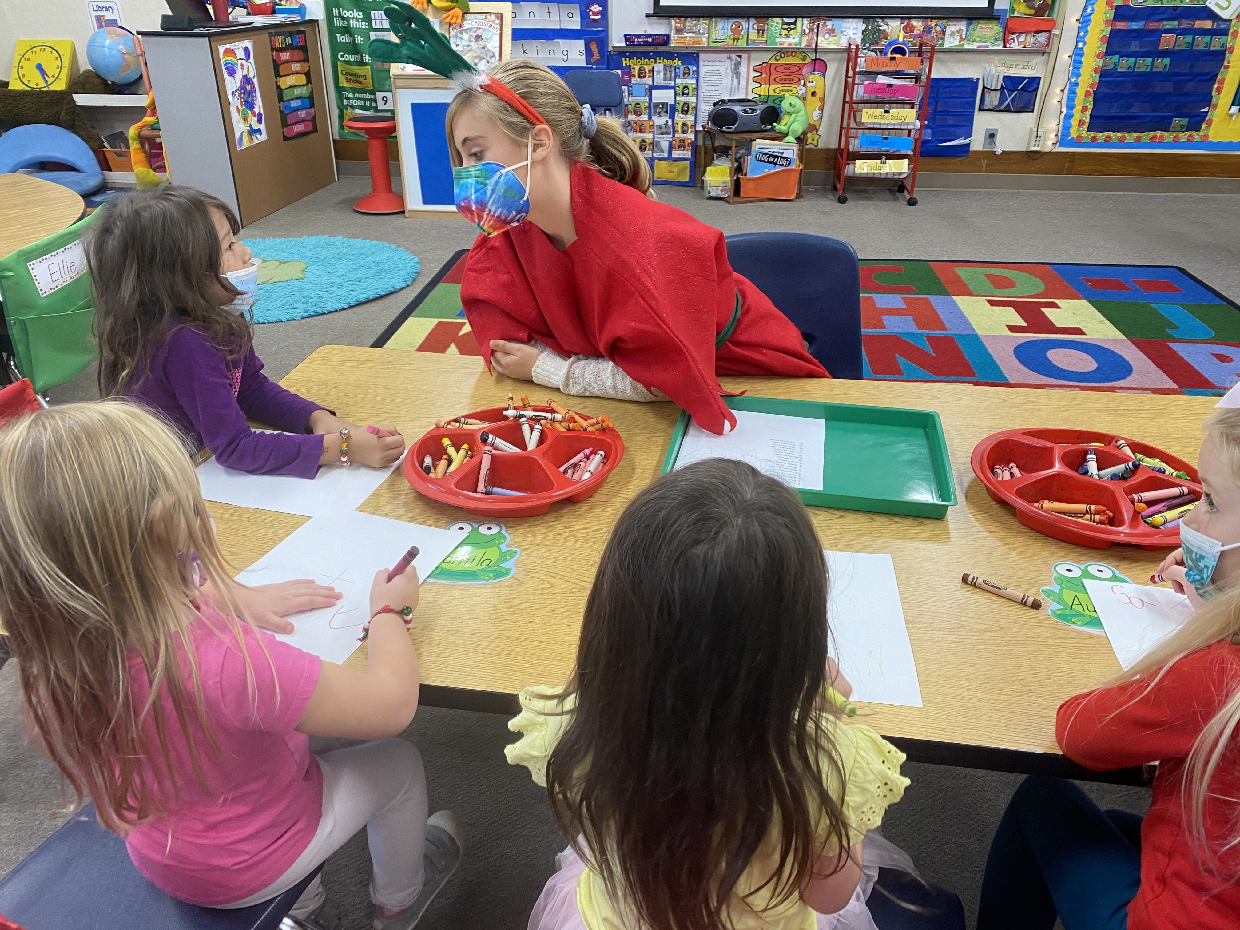 High school student dressed as reindeer entertains children with art projects.