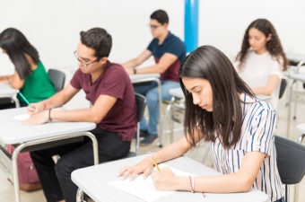 Group of teenage pupils taking test in classroom at university.