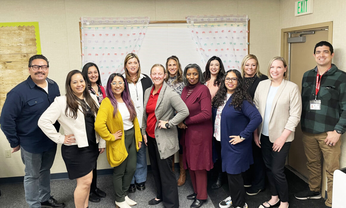 A group of teachers pose for a photography inside a classroom.