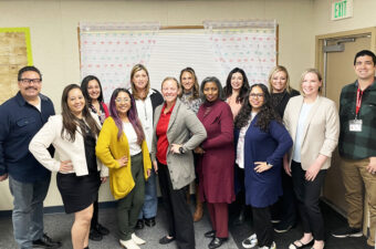 A group of teachers pose for a photography inside a classroom.