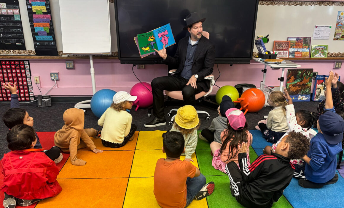 CTA President David Goldberg holding an open book sand reading to a classroom of small children.