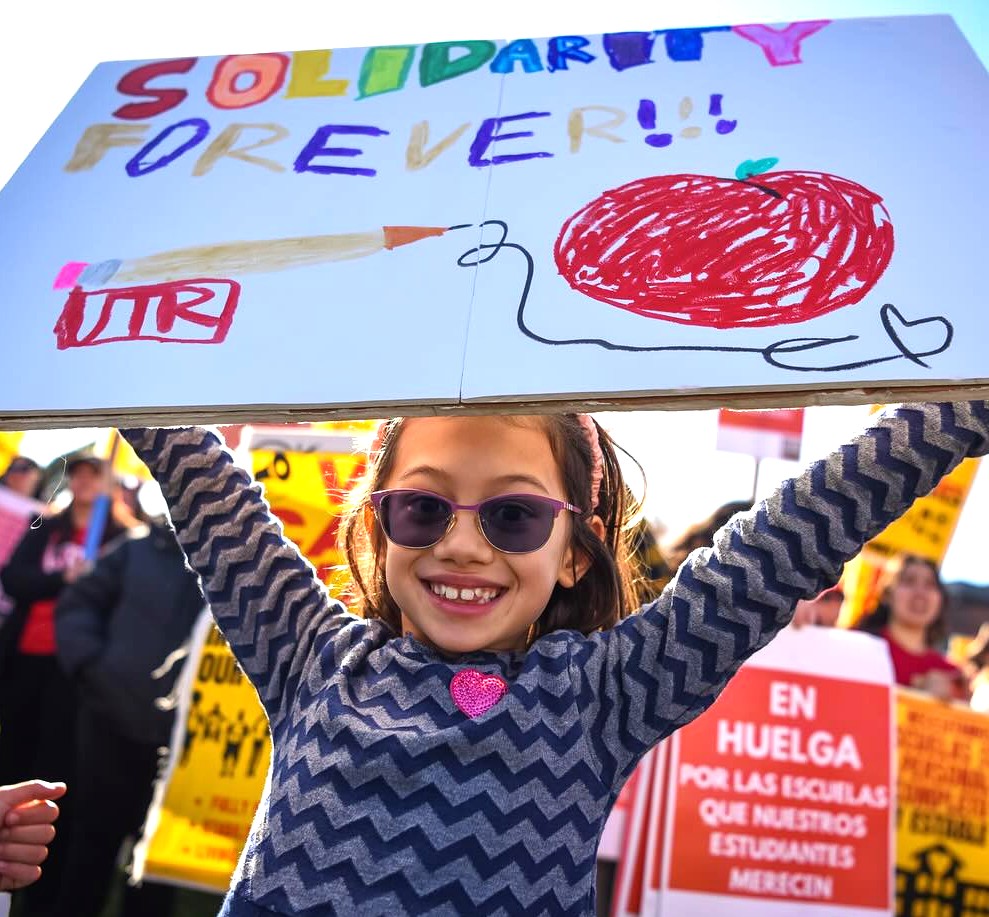 Photo of little girl at UTR strike holding solidarity forever sign.